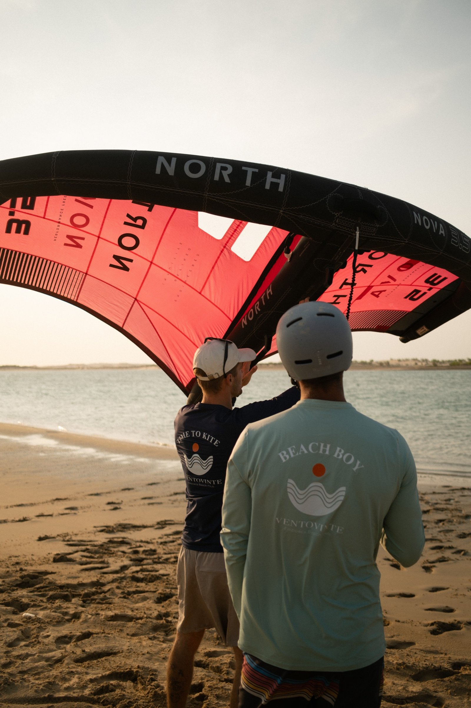 Instructor and student under a red North kite during a lesson on Emboaca bay