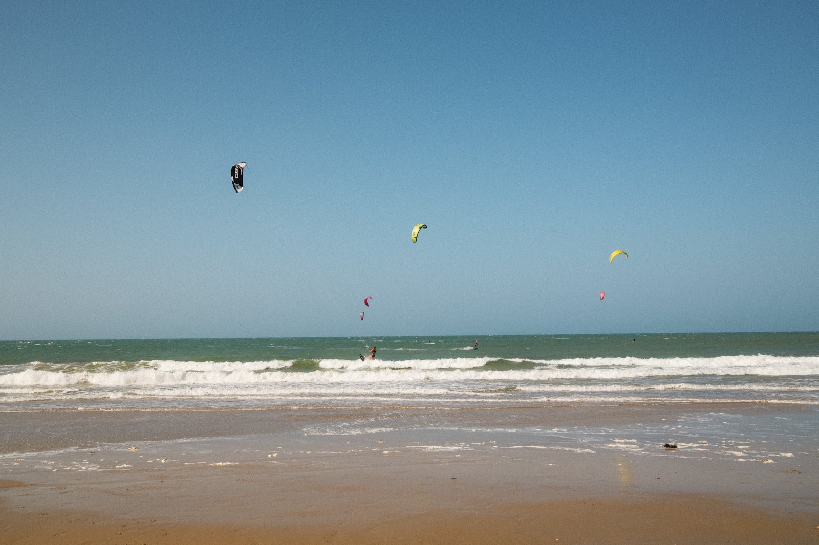 Kitesurfers riding the waves at Emboaca beach, colorful kites over the Atlantic