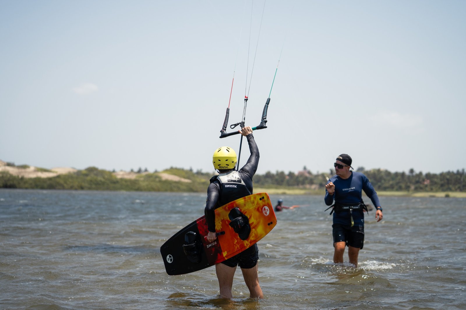 Student holding the board in waist-deep water, instructor at their side