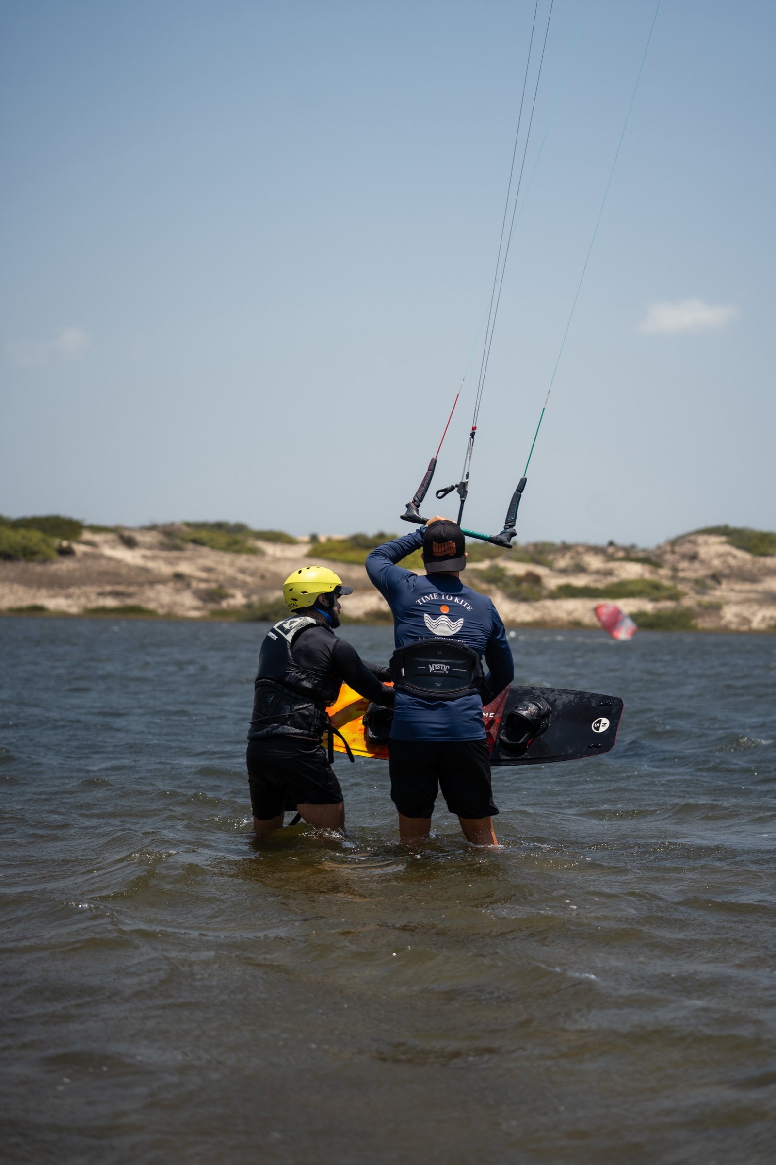 Instructor guiding a student's kite control in waist-deep water