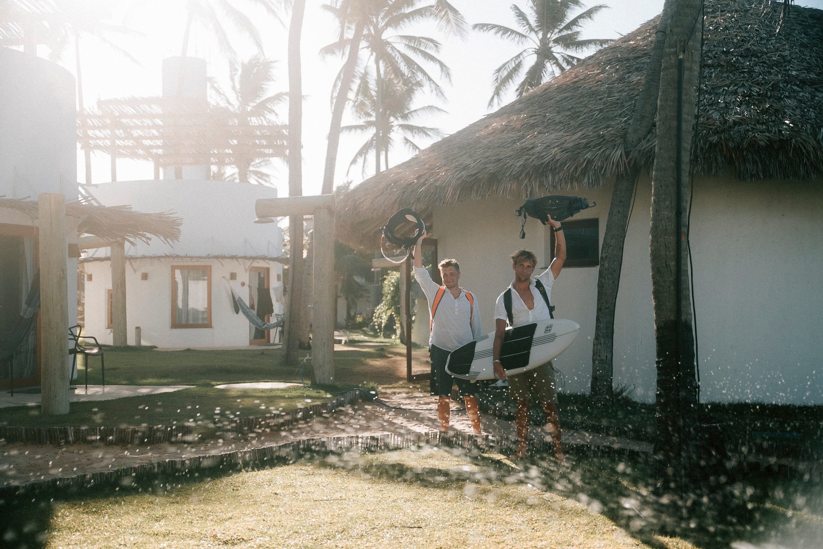 Two surfers carrying boards through the palm gardens of the Beach Club