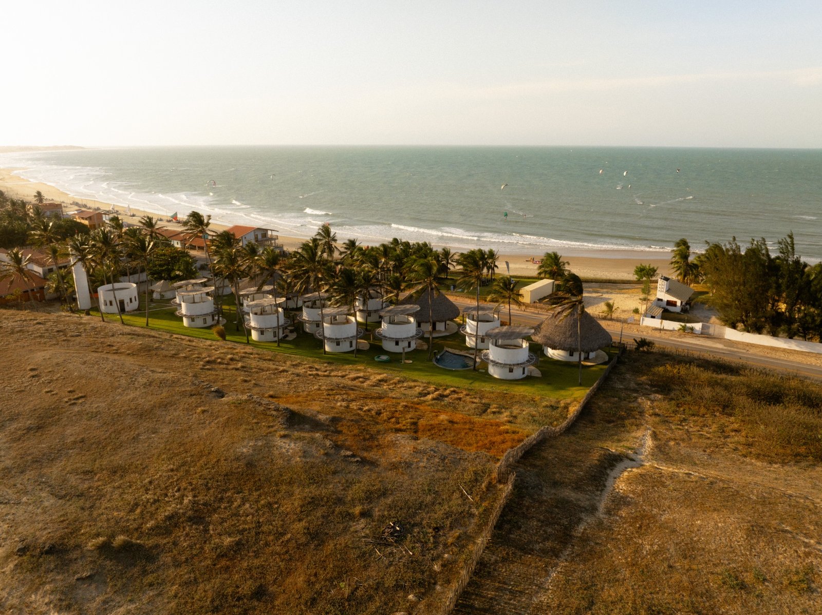 Aerial view of the Emboaca coastline with the Beach Club bungalows above the beach and kites on the water