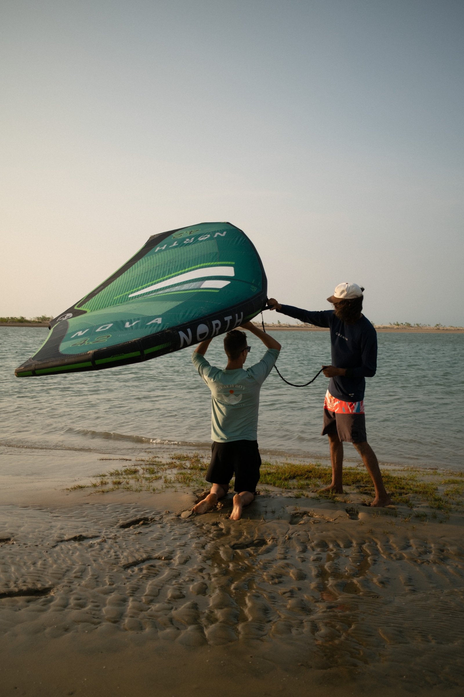 Instructor guiding a student holding the wing on the lagoon shore